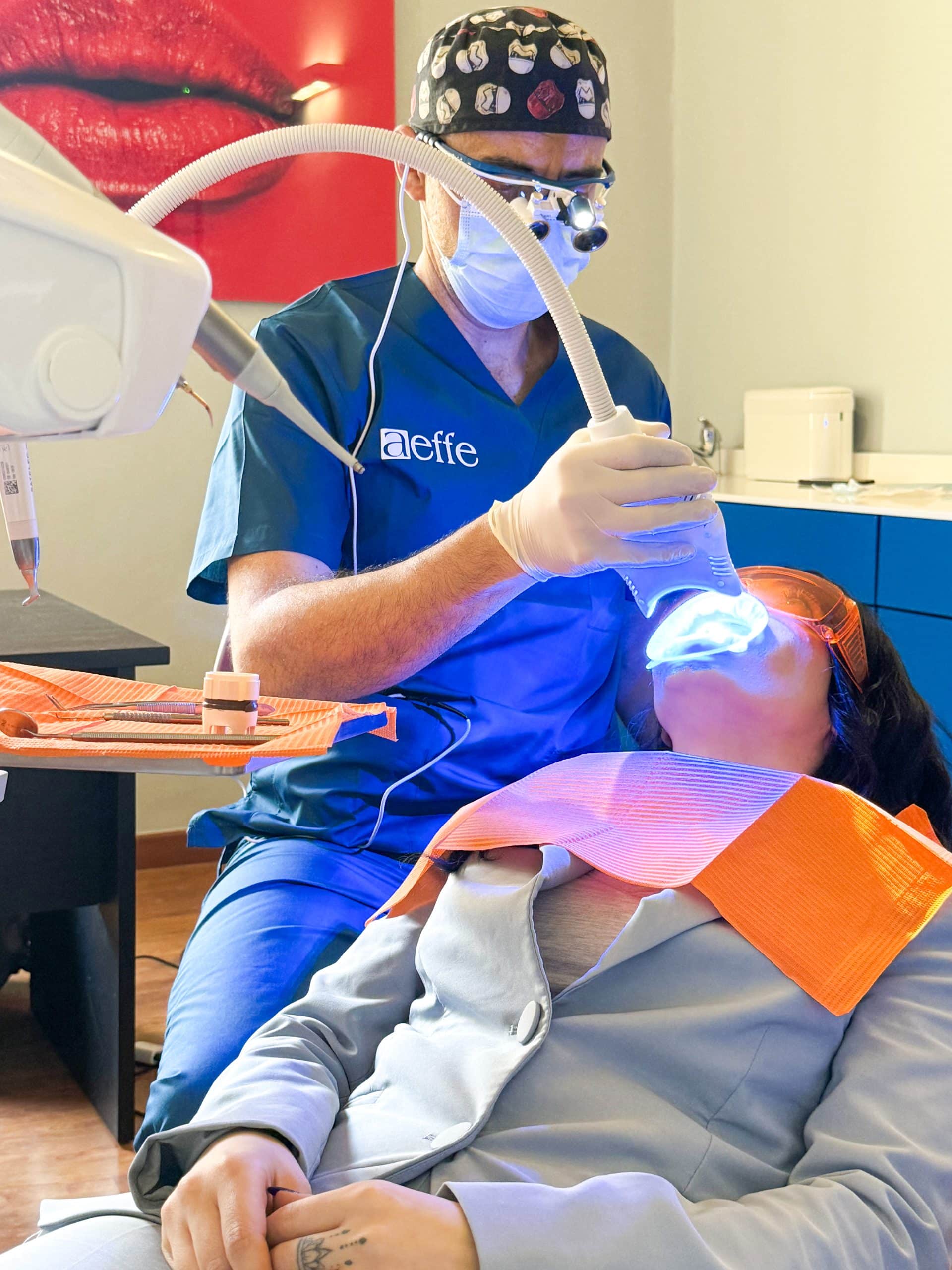 Dentista esegue trattamento dentale con luce blu su paziente.