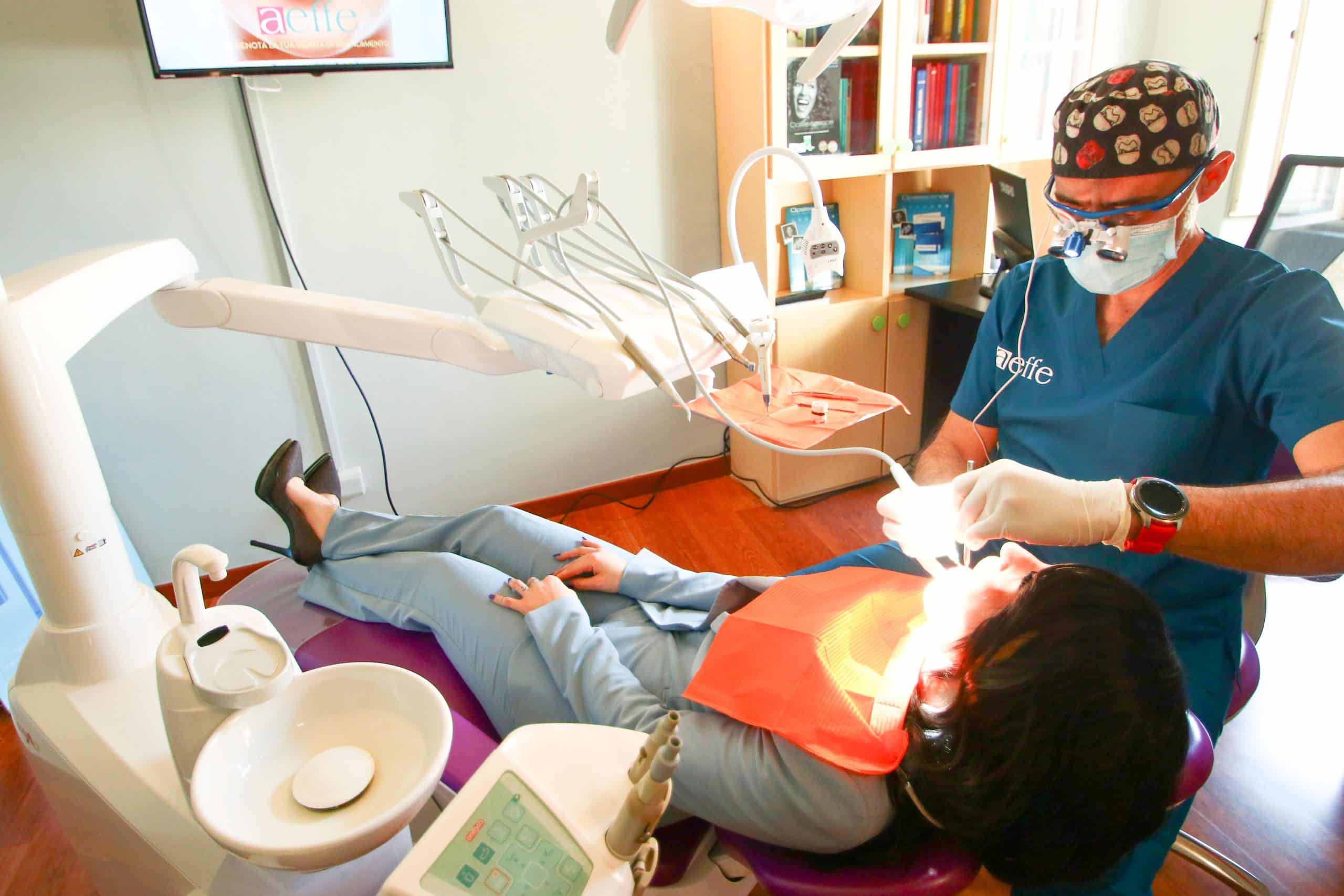 Dentista cura paziente su poltrona odontoiatrica.