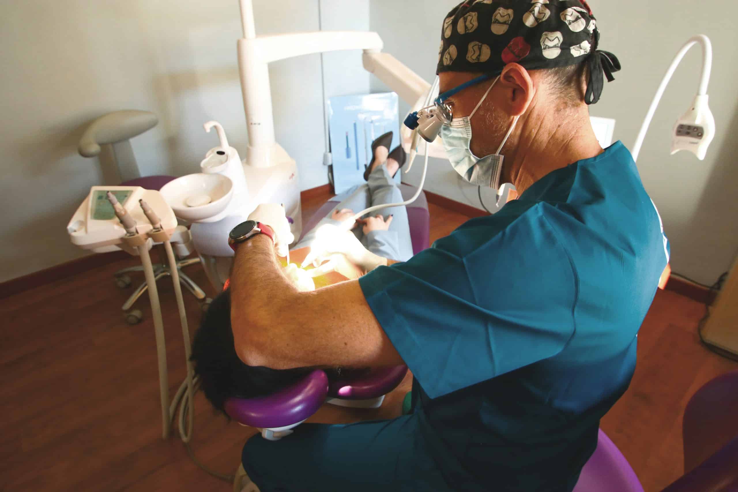 Dentista cura paziente su poltrona odontoiatrica.