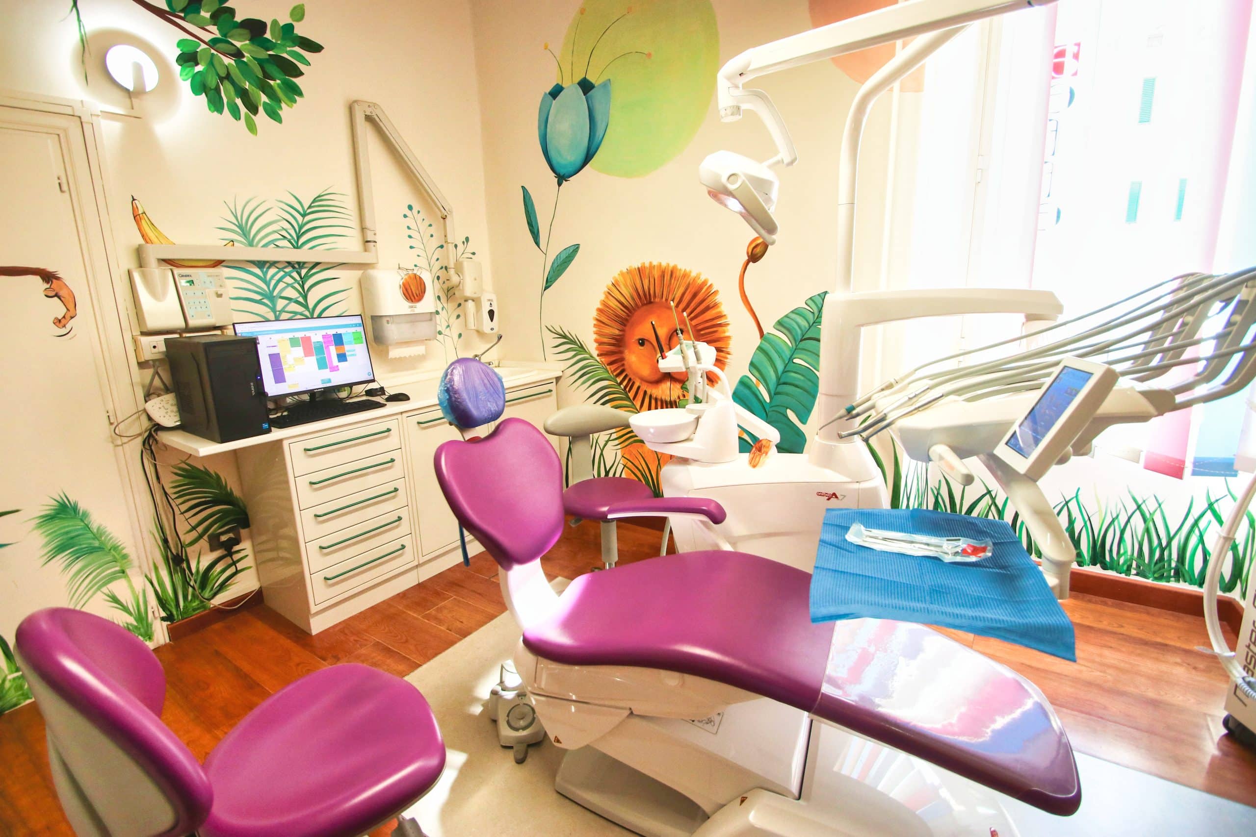 Studio dentistico colorato con poltrona viola e decorazioni murali.