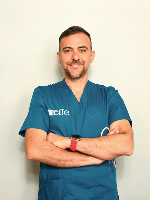 Uomo in uniforme medica blu con braccia incrociate.